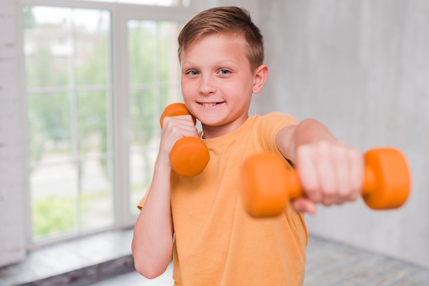 Portrait of a smiling boy exercising with dumbbell