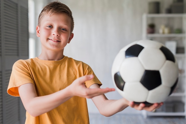 Free Photo portrait of a smiling boy showing soccer ball