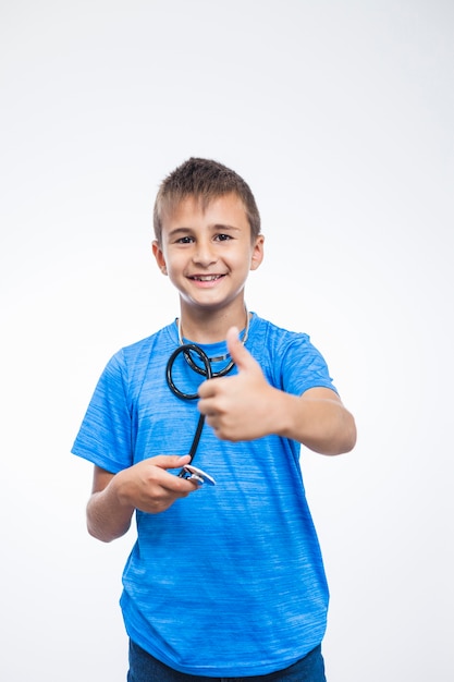 Portrait of a smiling boy with stethoscope gesturing thumbs up