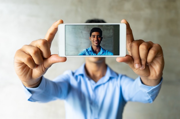 Portrait of smiling businessman taking selfie with smartphone.