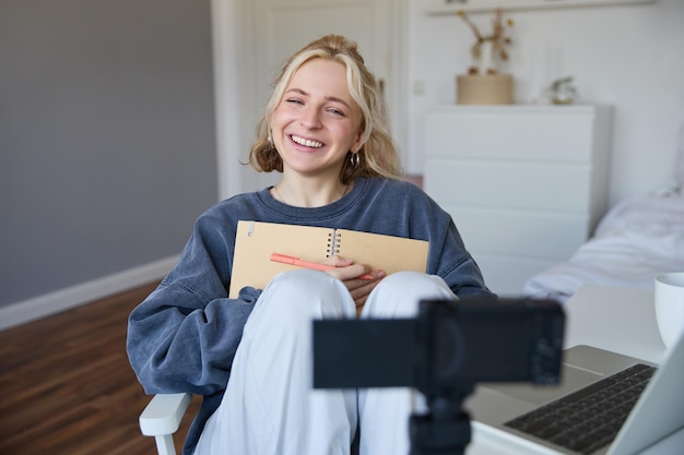 Free photo portrait of smiling charismatic young woman content creator records video on digital camera laughing