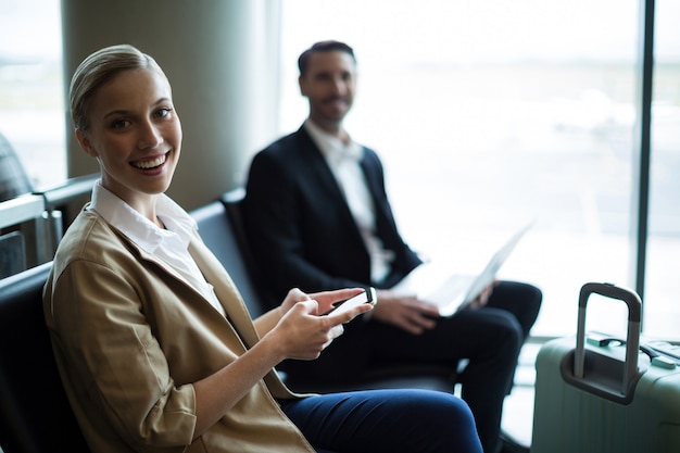 Free photo portrait of smiling commuters sitting in waiting area