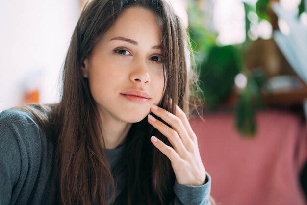 Portrait of smiling cute hipster girl staring on camera while writing college exercises in notebook.