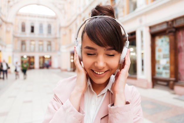 Free Photo portrait of a smiling cute young woman listening music with earphones