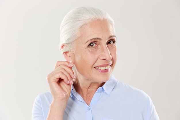 Portrait of smiling elderly woman touching her ear