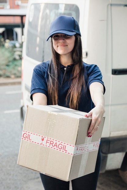 Free photo portrait of a smiling female courier with cardboard box