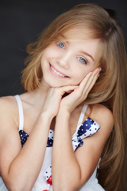 Portrait of smiling girl in a dress with long hair. Isolated on grey