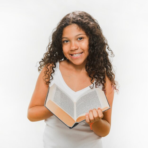 Portrait of smiling girl holding book over white background