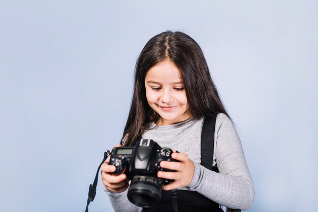 Portrait of a smiling girl looking at camera against blue backdrop