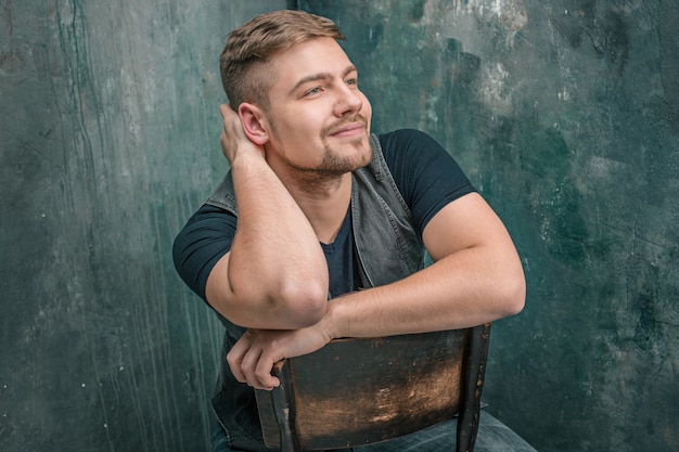 Portrait of smiling happy man sitting on the chair in studio