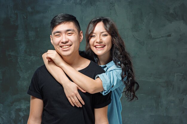 Portrait of smiling Korean couple on a gray studio background