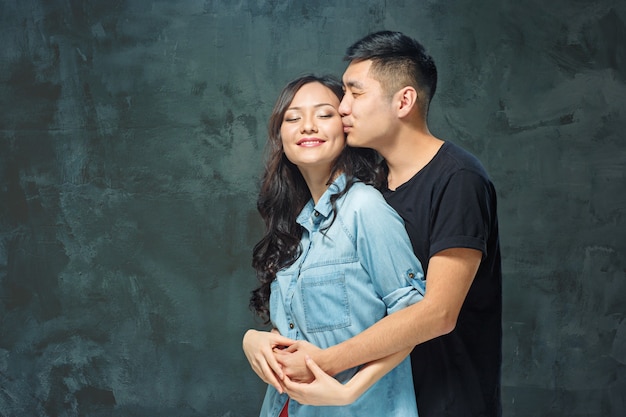 Portrait of smiling Korean couple on a gray studio background