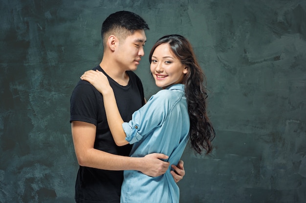 Portrait of smiling Korean couple on a gray wall