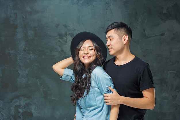 Portrait of smiling Korean couple on a gray wall