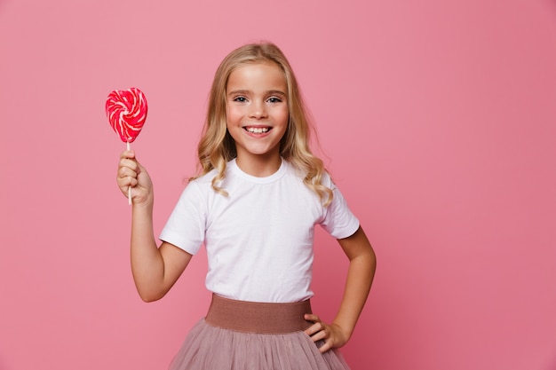 Free photo portrait of a smiling little girl holding heart shaped lollipop