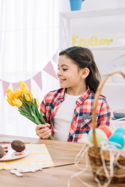 Portrait of a smiling little girl holding yellow tulip flowers on easter day