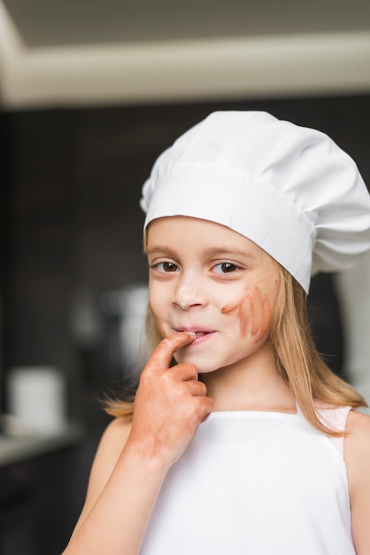 Free photo portrait of smiling little girl putting her finger in mouth