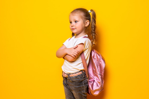 Free Photo portrait of a smiling little schoolgirl with backpack on yellow wall