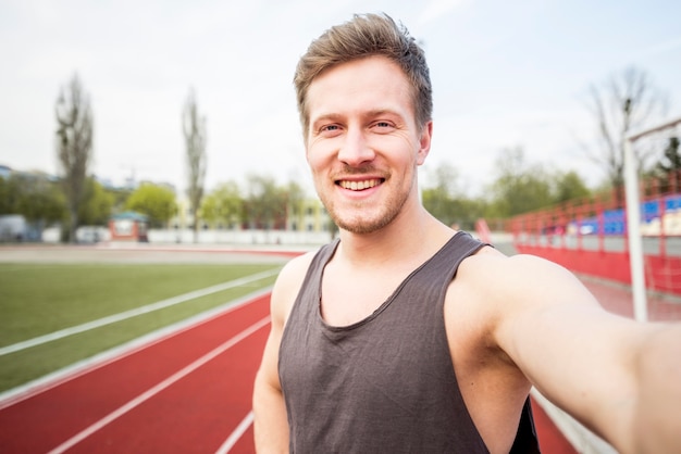 Free photo portrait of smiling male athlete talking selfie on mobile phone