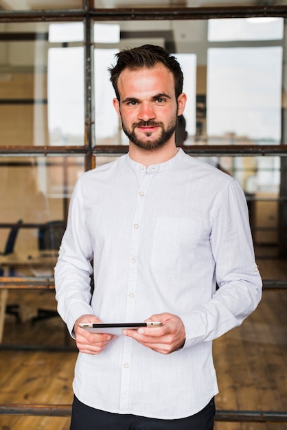 Free photo portrait of smiling man holding digital tablet looking at camera