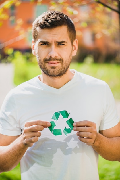 Portrait of smiling man holding recycle icon in the park