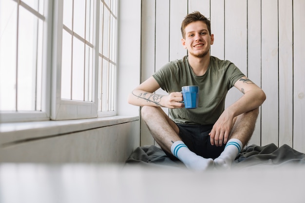 Free photo portrait of smiling man looking at camera holding coffee cup