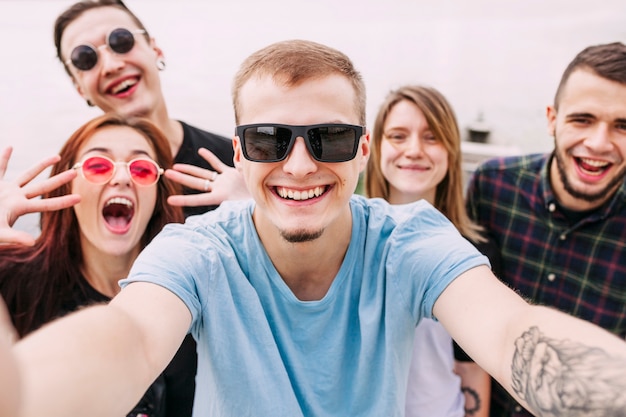 Free photo portrait of smiling man taking selfie with friends