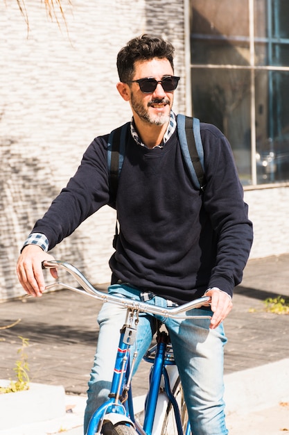 Portrait of a smiling man wearing sunglasses riding on his bicycle