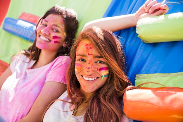 Free photo portrait of a smiling two young women with holi color face