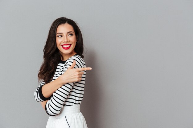 Portrait of a smiling woman pointing finger away