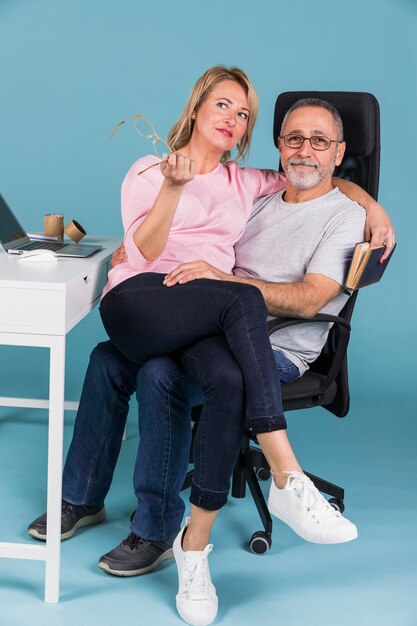 Portrait of a smiling woman sitting on mans lap while sitting on chair