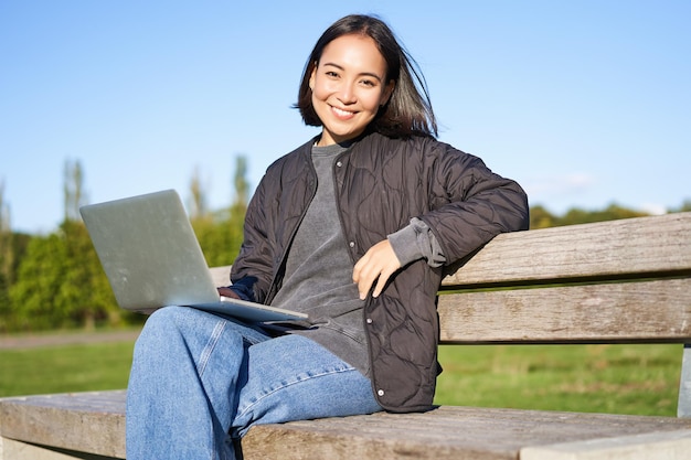 Portrait of smiling woman sitting with laptop working on project or studying remotely enjoying being