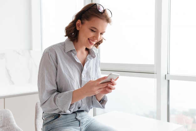 Free Photo portrait of a smiling woman texting on mobile phone