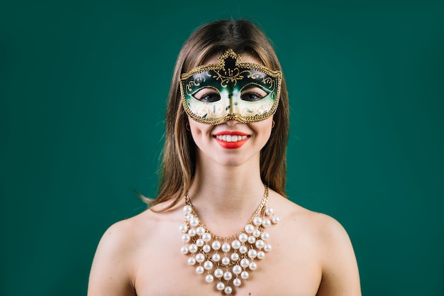 Free Photo portrait of a smiling woman wearing carnival mask on colored background