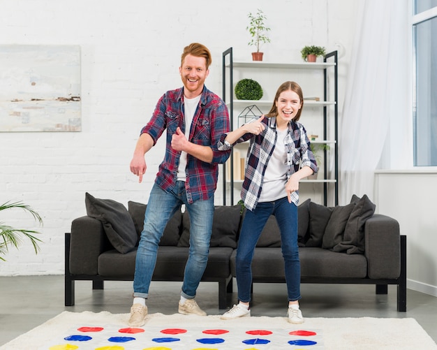 Free Photo portrait of a smiling young couple pointing the finger over the color dot game showing thumb up sign