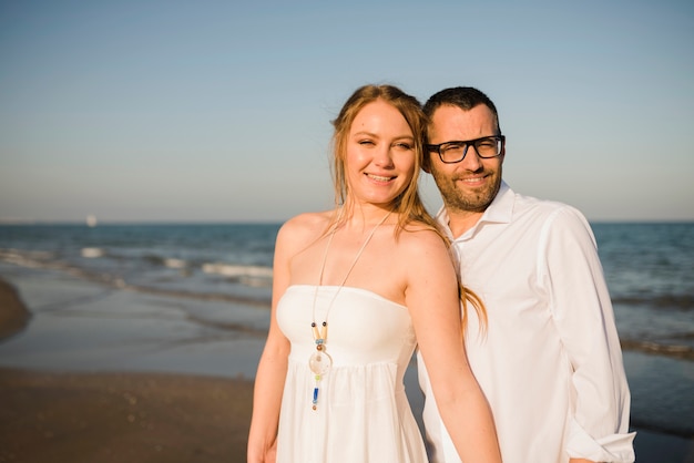 Portrait of smiling young couple standing near the sea at beach