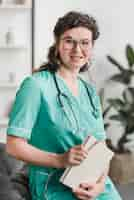 Free photo portrait of smiling young female nurse sitting on sofa