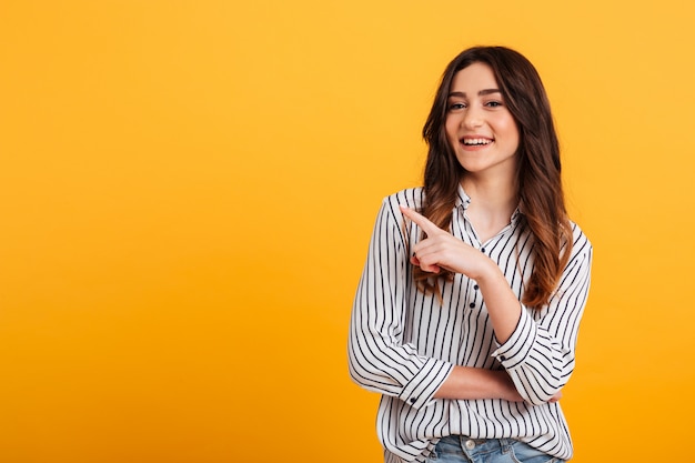 Portrait of a smiling young girl pointing finger away