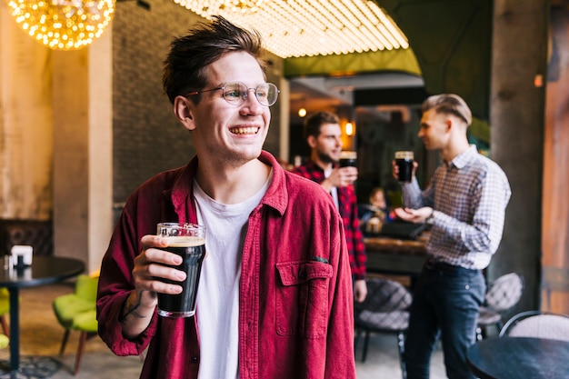 Portrait of a smiling young man holding the beer glass enjoying