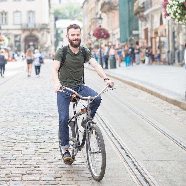 Free photo portrait of a smiling young man riding bicycle at outdoors