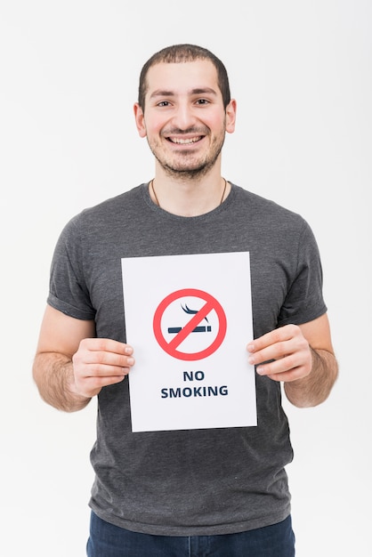 Free photo portrait of a smiling young man showing no smoking sign isolated on white backdrop