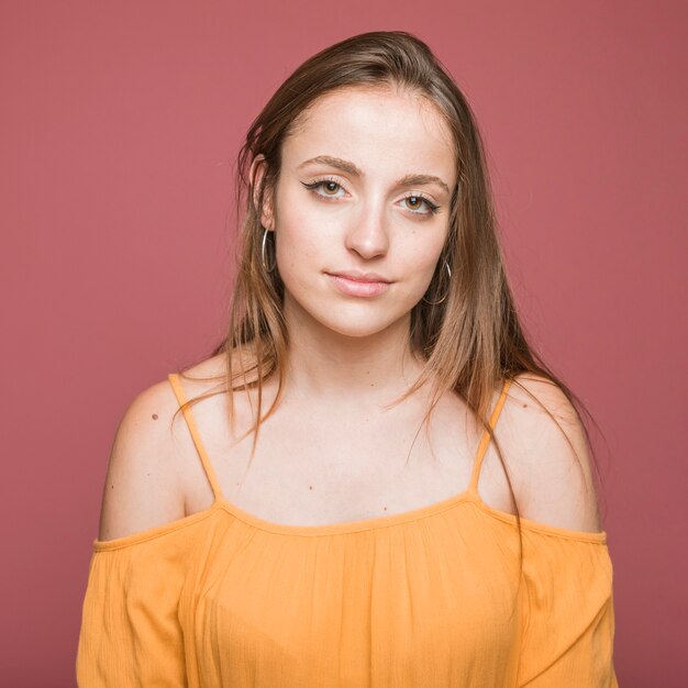 Portrait of smiling young woman against brown background