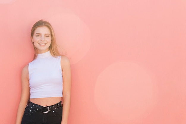 Portrait of a smiling young woman against peach background