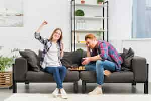 Free photo portrait of a smiling young woman cheering after winning the chess game in the living room