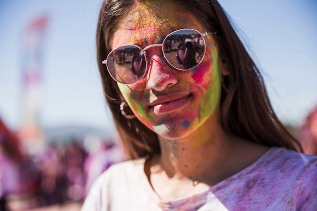 Free photo portrait of a smiling young woman covered her face with holi powder