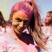 Free photo portrait of a smiling young woman covered with holi color