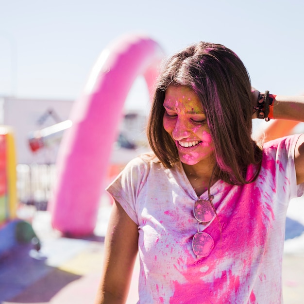 Free photo portrait of a smiling young woman covered with pink holi color