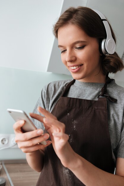 Portrait of a smiling young woman in headphones wearing apron