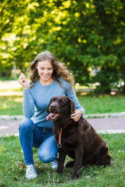 Portrait of a smiling young woman and her dog in garden