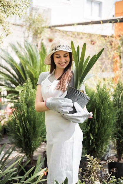 Free photo portrait of a smiling young woman looking at pot plant hold in her hands